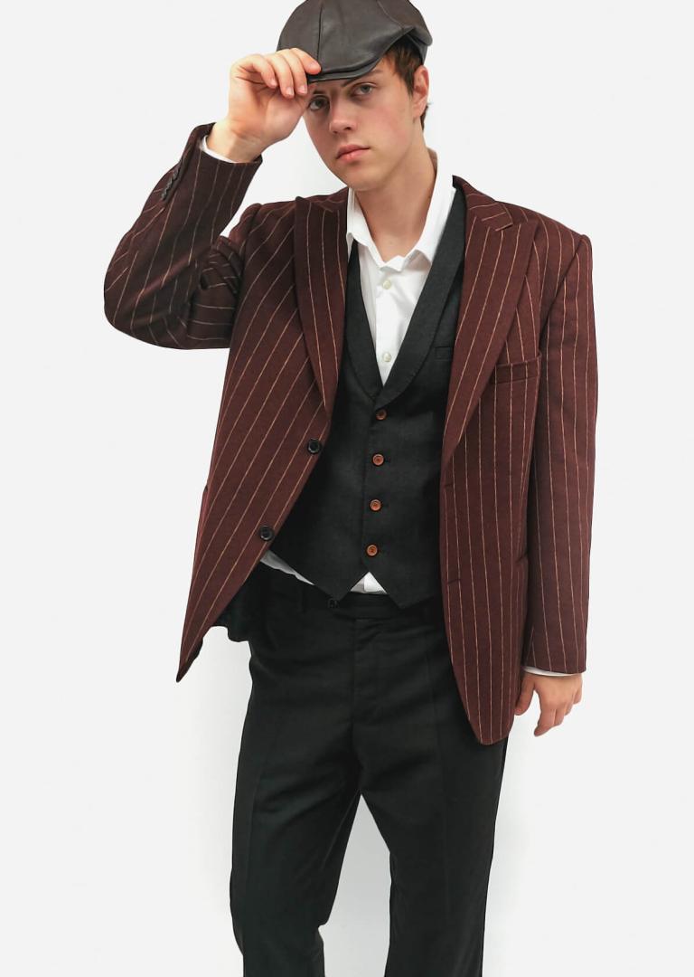 Чоловік у темно-червоному смугастому піджаку, жилетці та шкіряній кепці в ретро-стилі 1920-х–30-х років