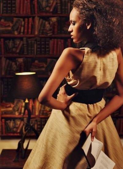 Бібліотечна муза 50-х Дівчина в елегантному вбранні 50-х років з книгою в руках на фоні бібліотеки