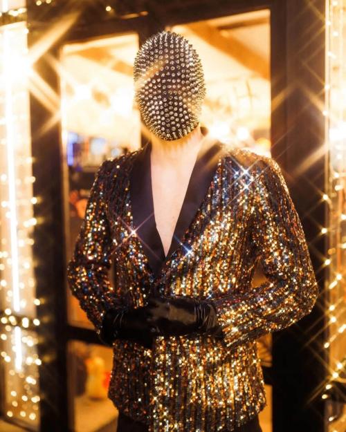 Чоловік у блискучому піджаку з паєтками та масці з шипами — сценічний ретро-образ