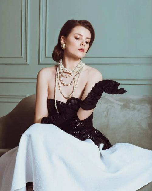 Класичний вечірній образ: чорна сукня, біла пишна спідниця, довгі рукавички та багатошарові перли