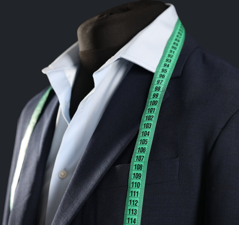 Чоловічий манекен з темним костюмом та перекинутим зеленим швацьким метром